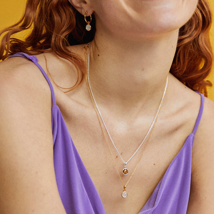 Model wearing a silver smoky quartz and a gold moonstone necklace and chain set.