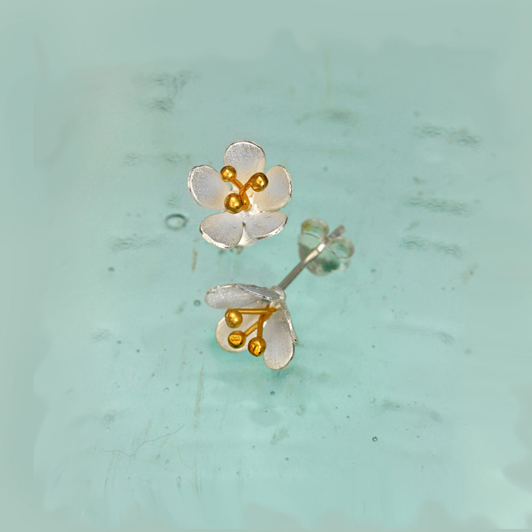 Silver floral post earrings with gold centers on a light green background