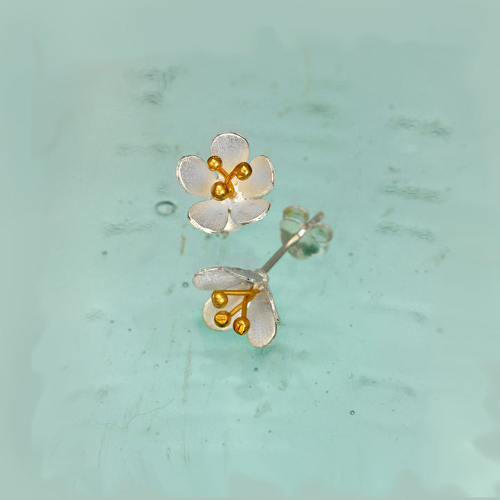 Silver floral post earrings with gold centers on a light green background