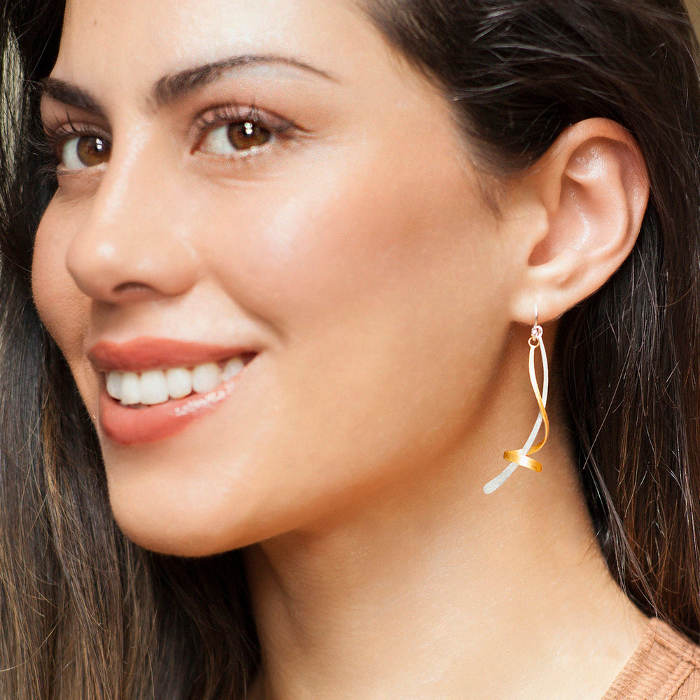 Close-up of a woman wearing a gold and silver twisted earring