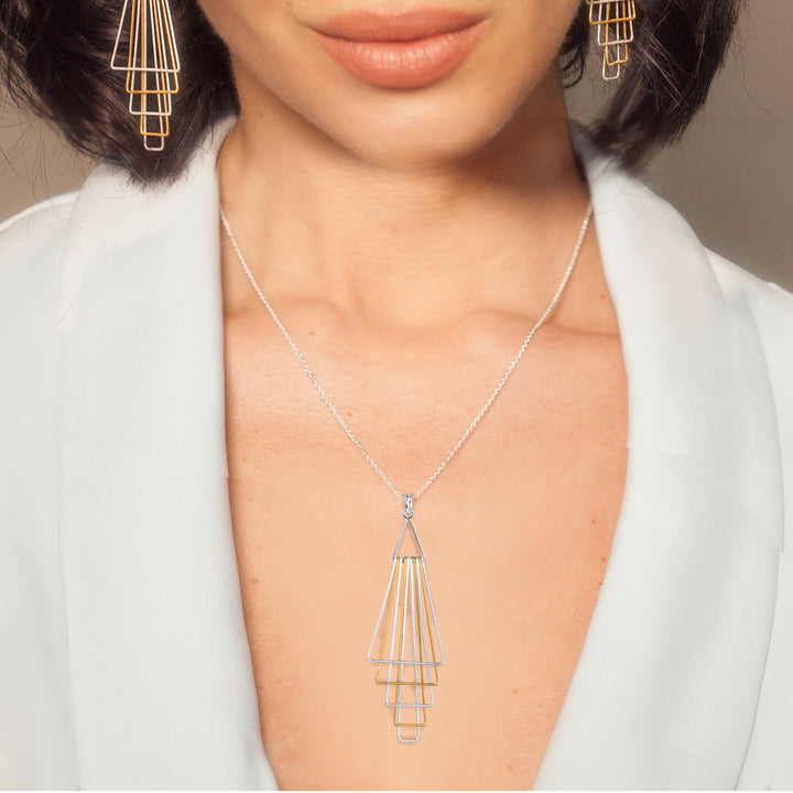 Close-up of a person wearing a silver and gold geometric pendant.