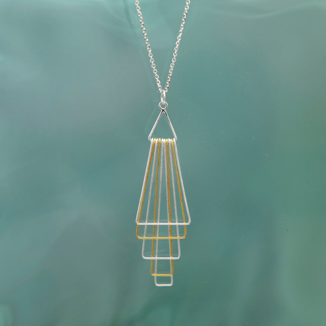 Silver and gold geometric necklace with on a green background