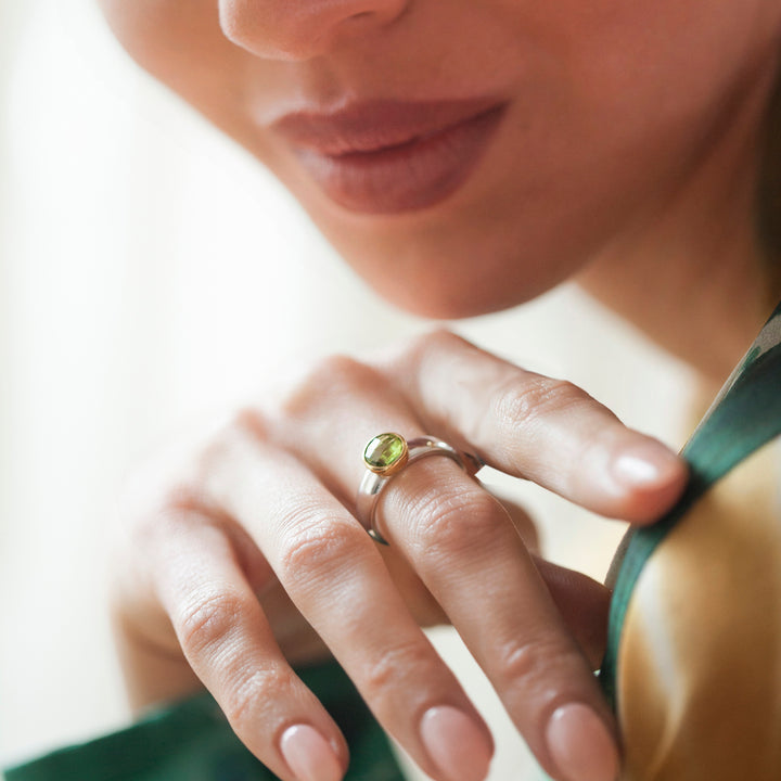 Close-up of a woman's hand wearing a ring with a green peridot gemstone.