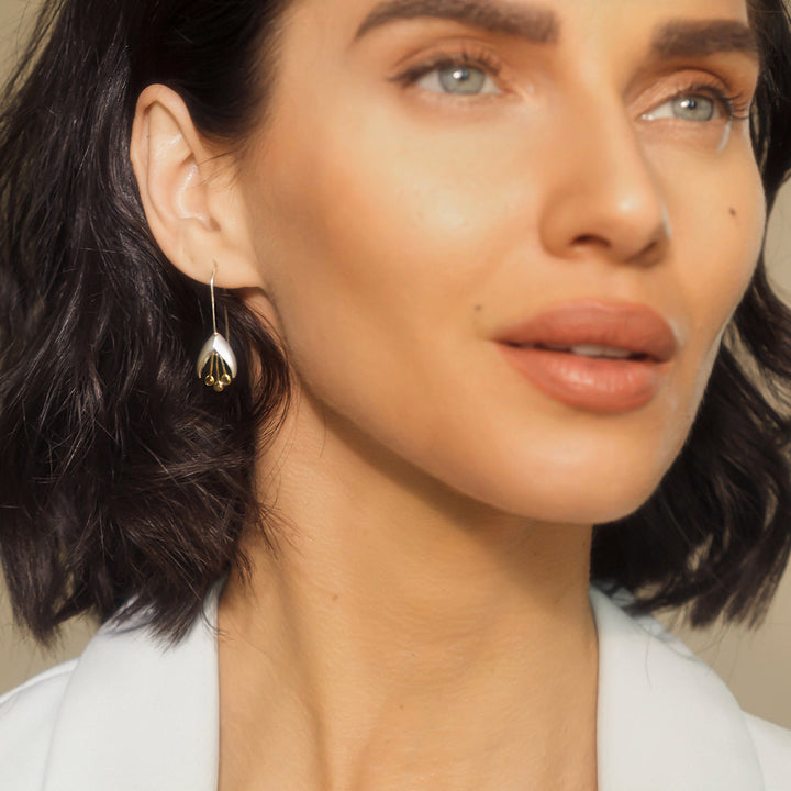 Close-up of a woman wearing silver and gold flower earrings
