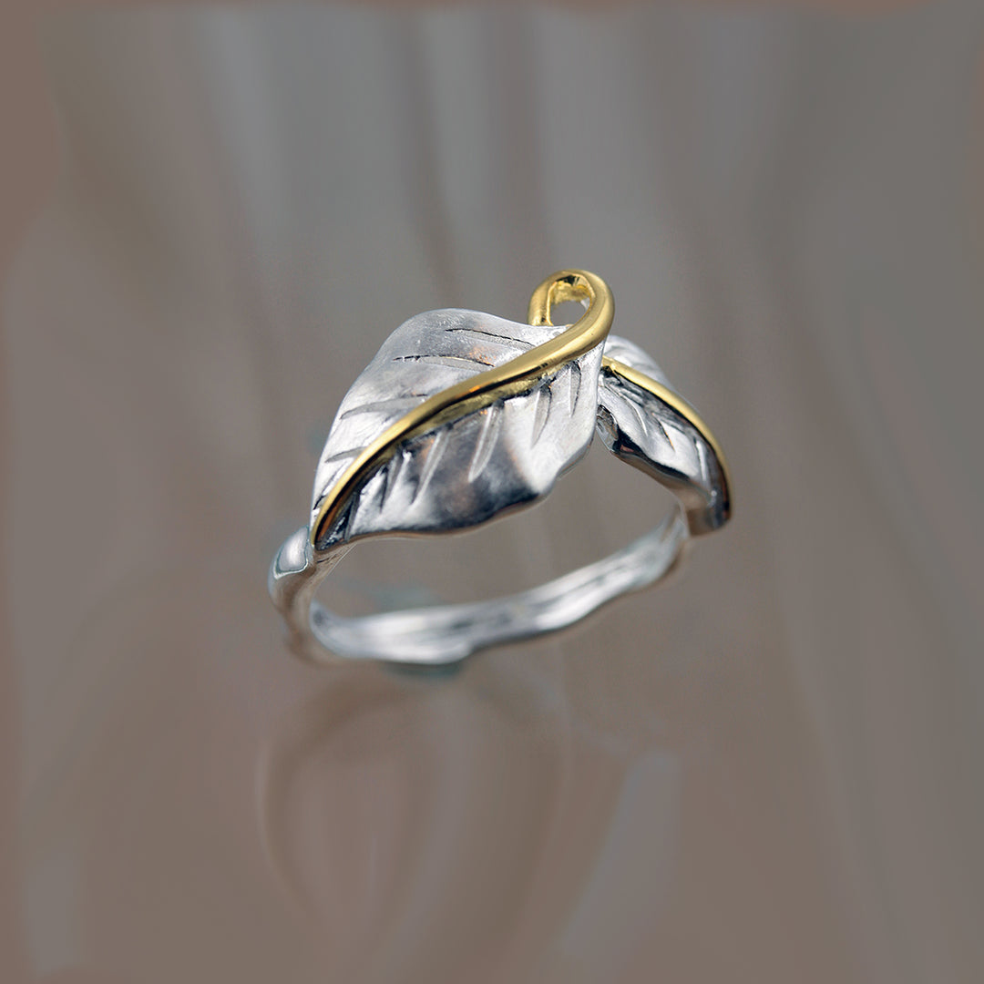 Silver double leaf ring with gold vermeil stems on reflective surface