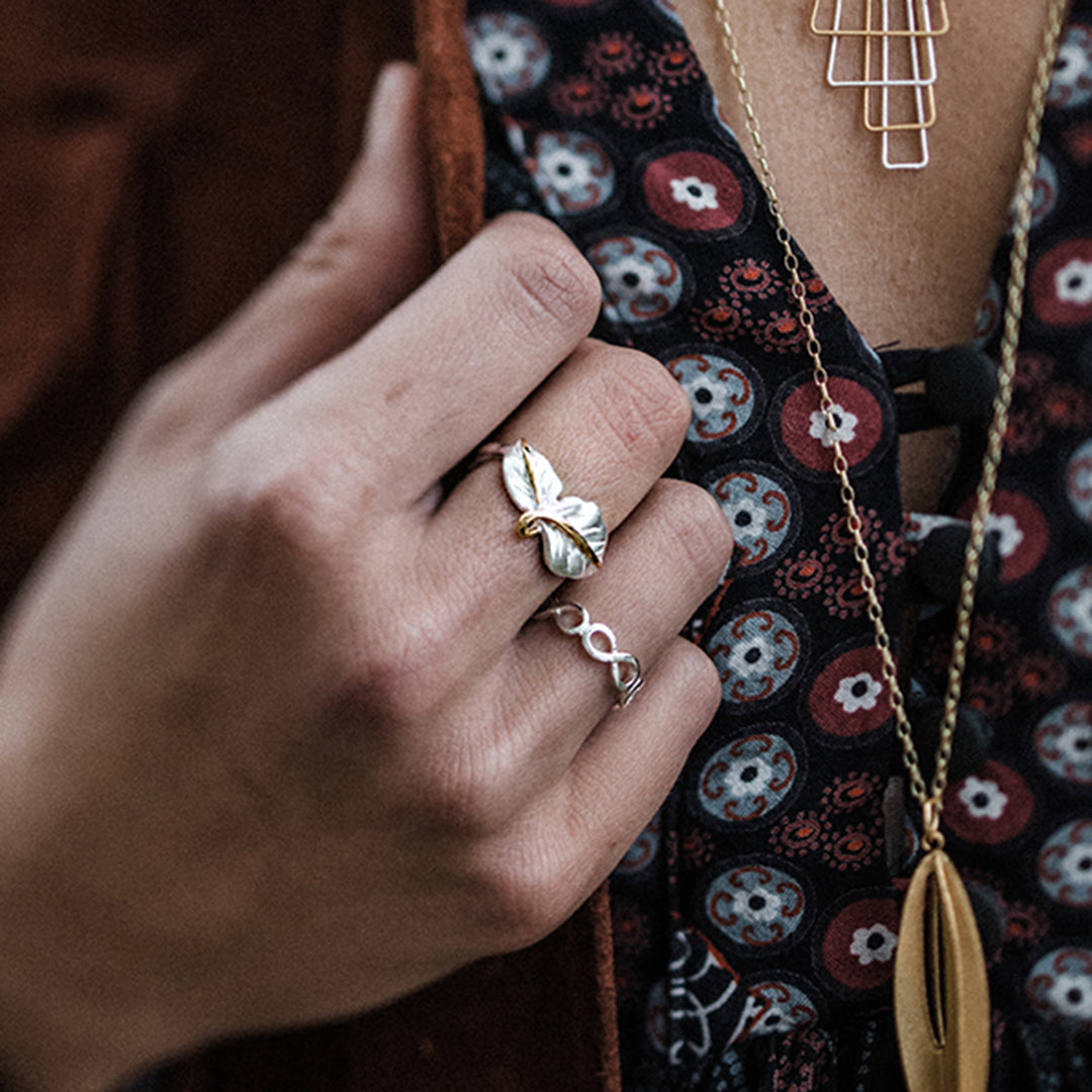 Model wearing a silver two leaf ring with gold details and other jewellery