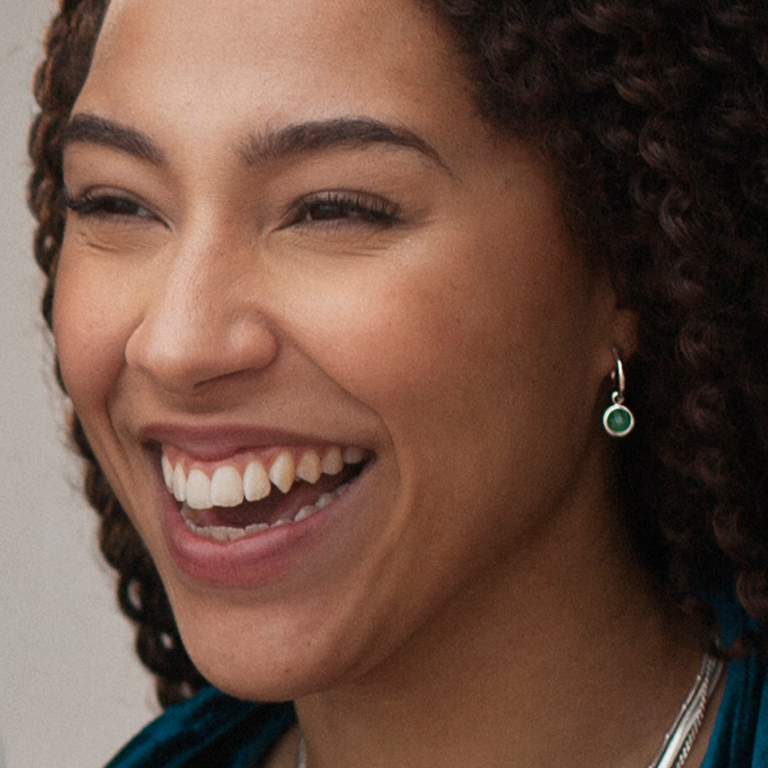 Model wearing silver hoop earrings with green quartz