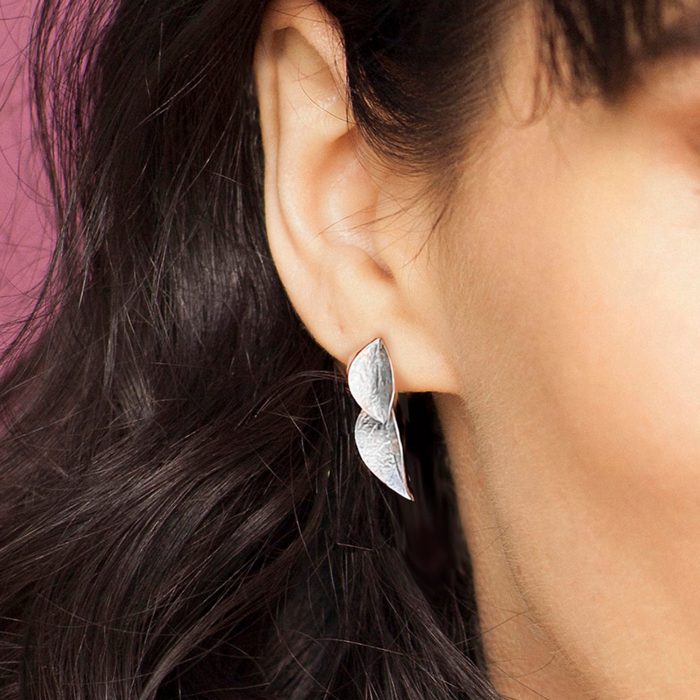 Close-up of woman wearing sterling silver twin leaf drop stud earrings