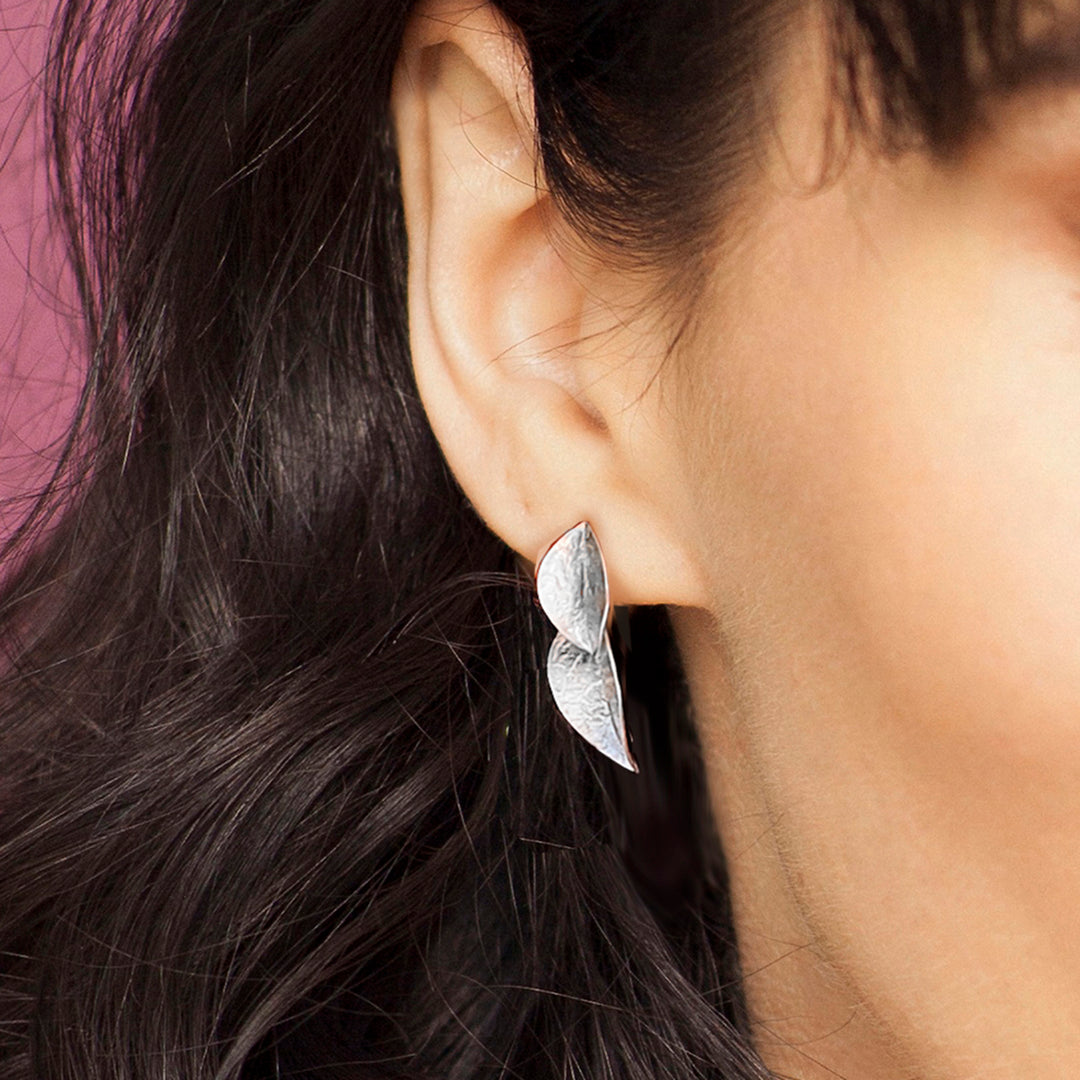 Close-up of woman wearing sterling silver twin leaf drop stud earrings