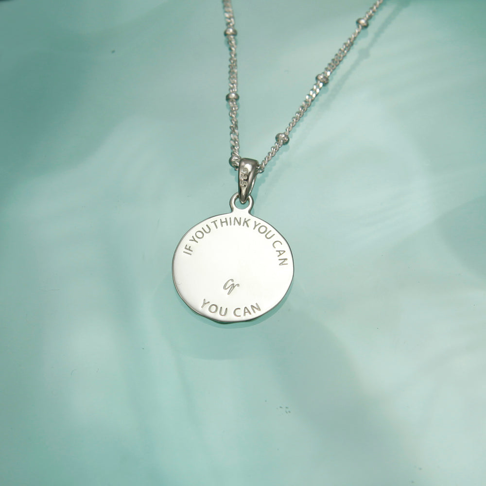 Reverse side of a lucky charm horseshoe necklace in silver showing hidden etched message.