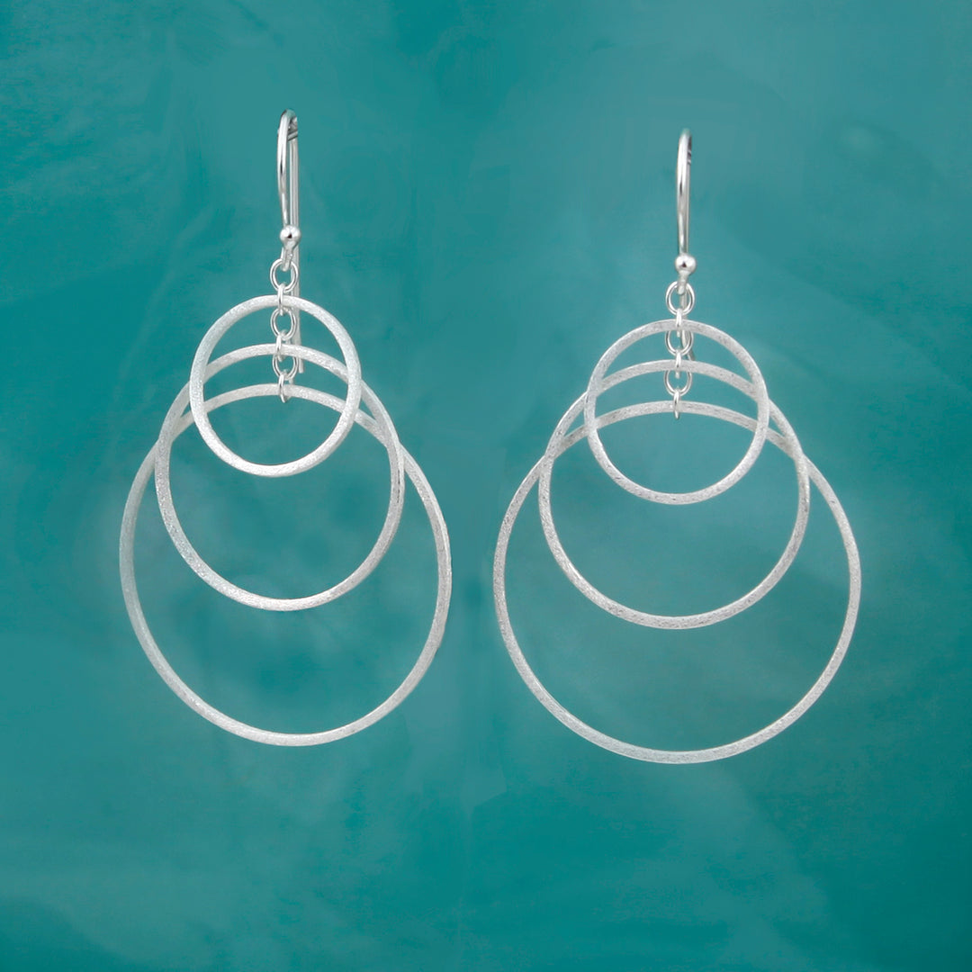 Silver hoop earrings on a teal background