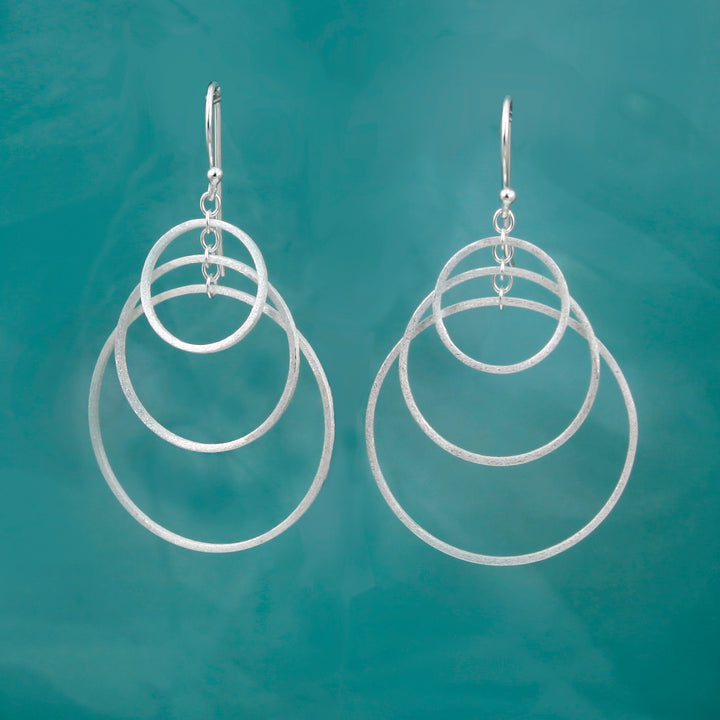 Silver hoop earrings on a teal background