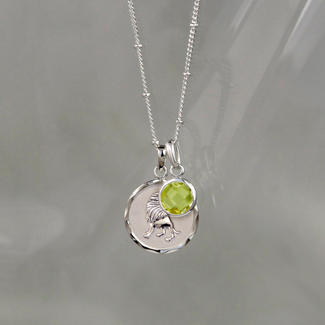 Silver Leo zodiac pendant and peridot August birthstone charm on gray background