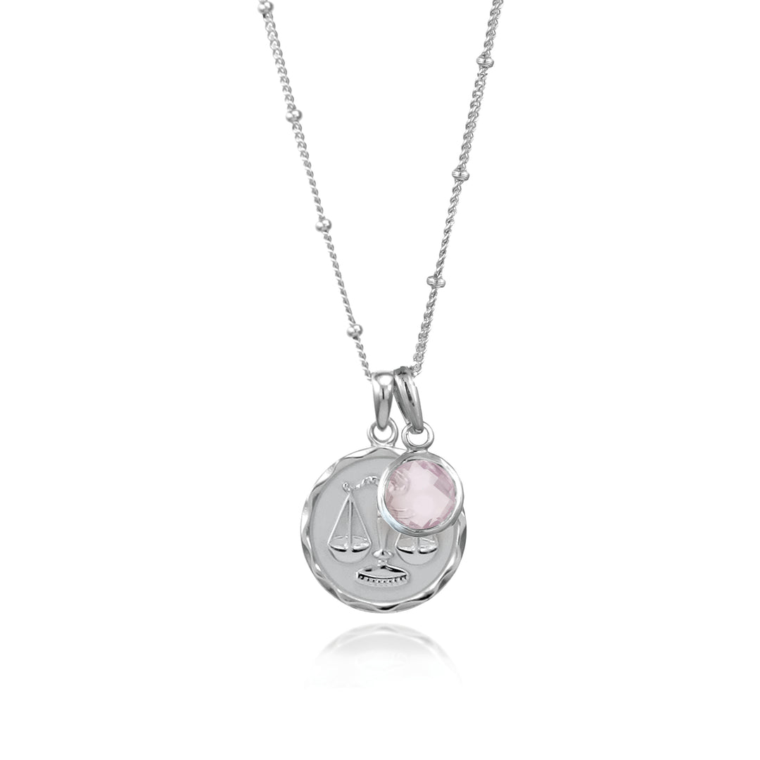 Silver Libra zodiac necklace and rose quartz October birthstone charm on a white background