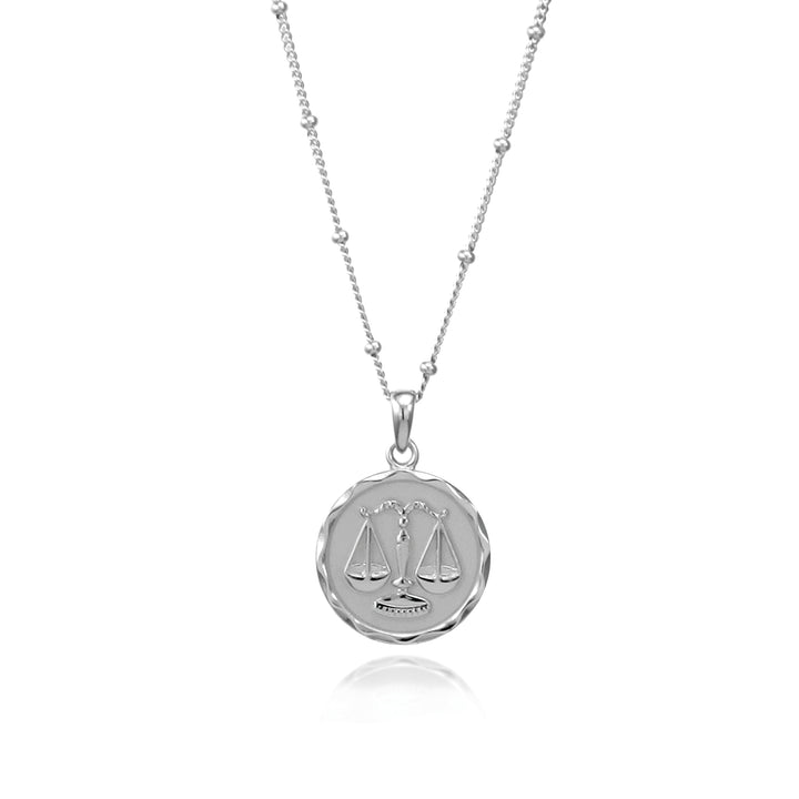 Silver Libra zodiac pendant and beaded chain on a white background