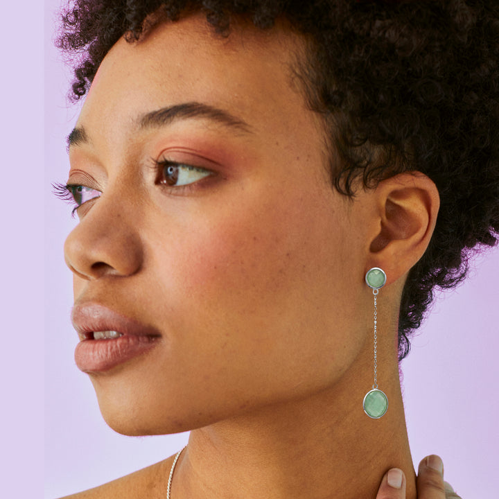 Side view of model wearing long silver green gemstone earrings on chains