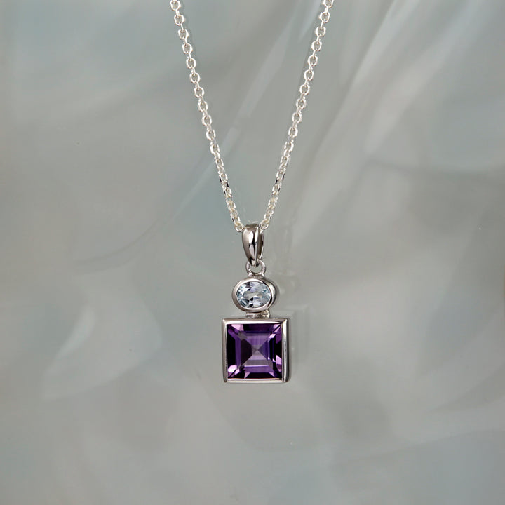 Silver necklace with a amethyst and blue topaz gemstones on a gray background