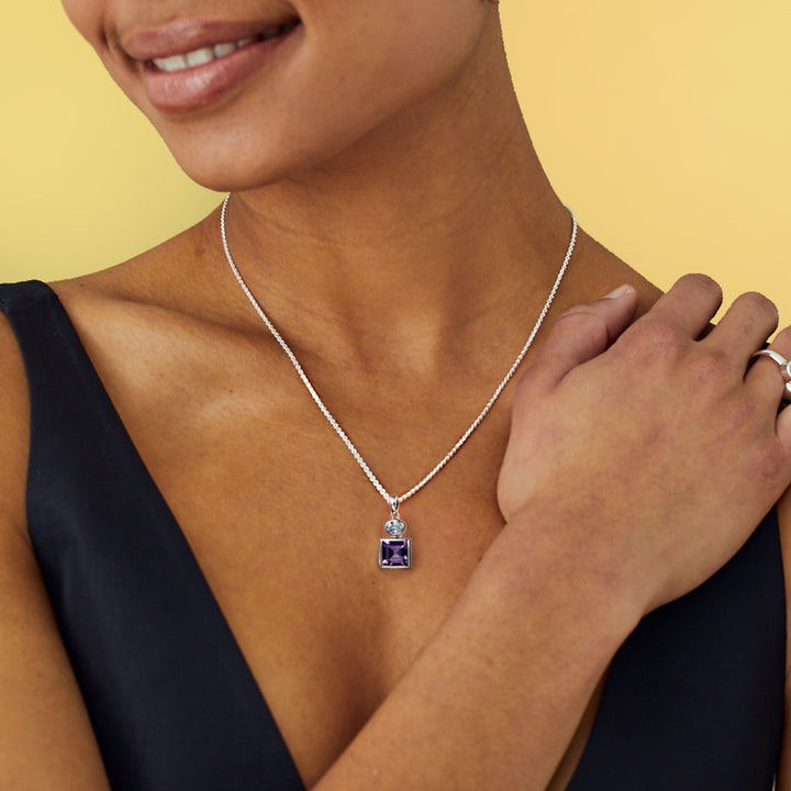 Woman wearing a silver necklace square amethyst and oval blue topaz gemstones