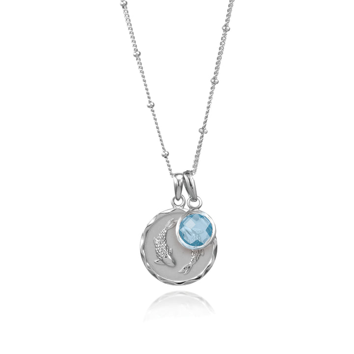 SIlver zodiac pendant and blue topaz gemstone charm on white background