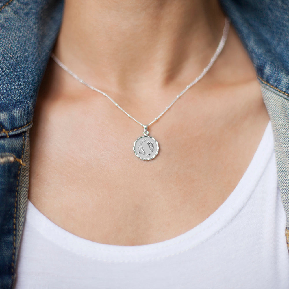 Model wearing a silver star sign pisces necklace and denim jacket
