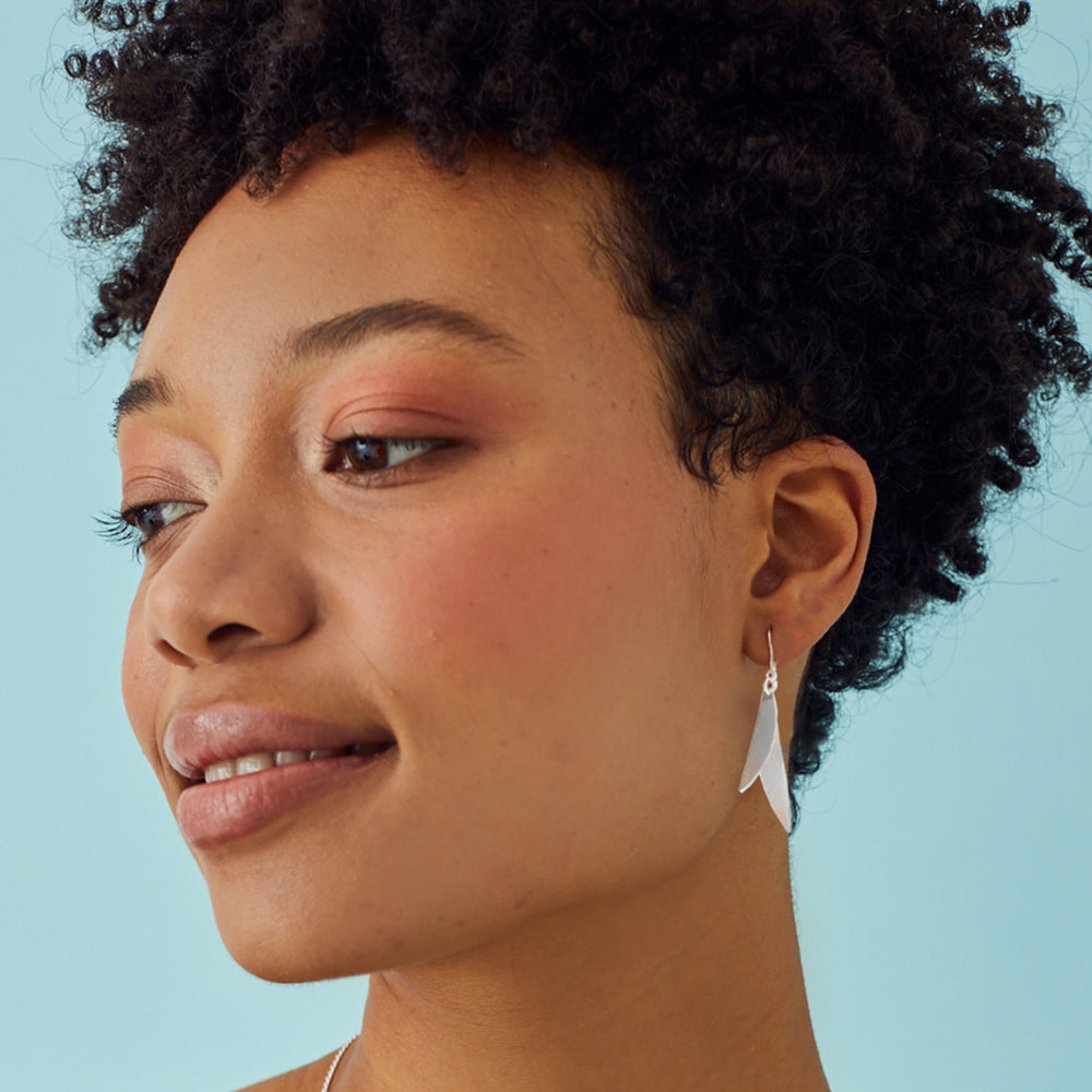 Silver drop earrings on model with blue background