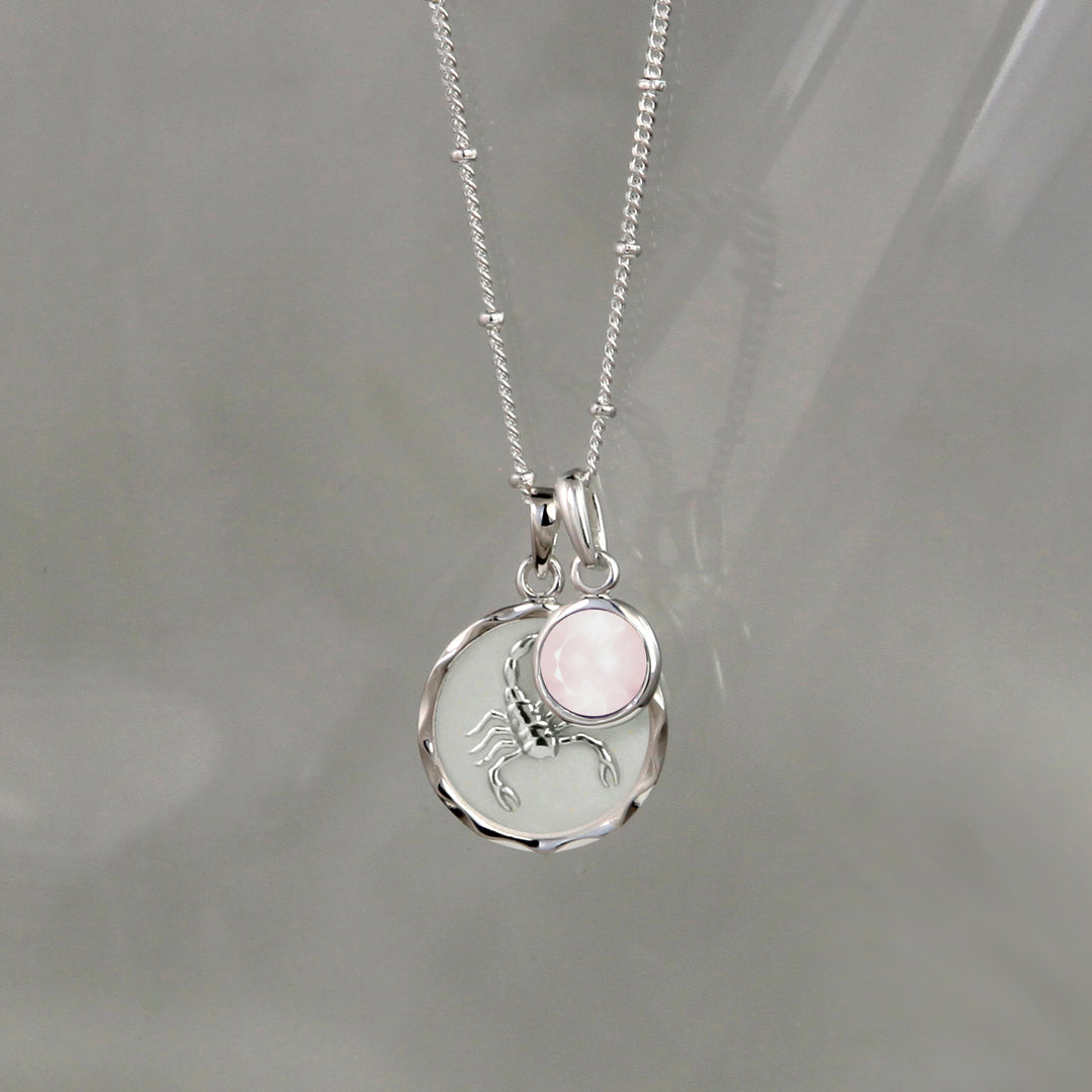 Silver zodiac zodiac pendant and rose quartz October birthstone charm on gray background