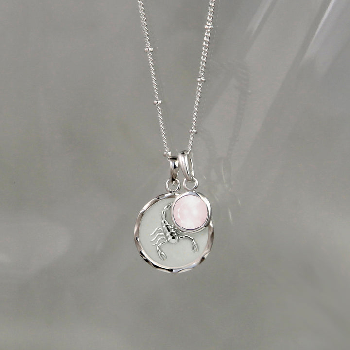 Silver zodiac zodiac pendant and rose quartz October birthstone charm on gray background