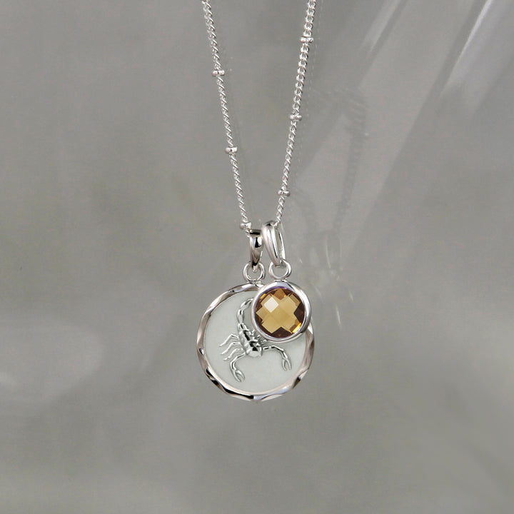 Silver zodiac zodiac pendant and smoky quartz November birthstone charm on gray background