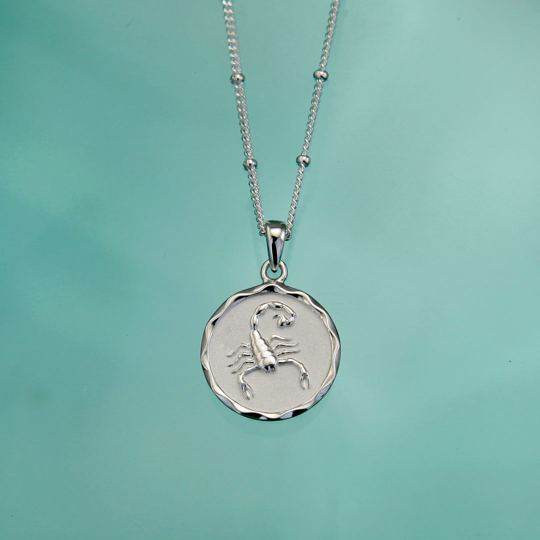 Silver zodiac star sign necklace on an aqua background