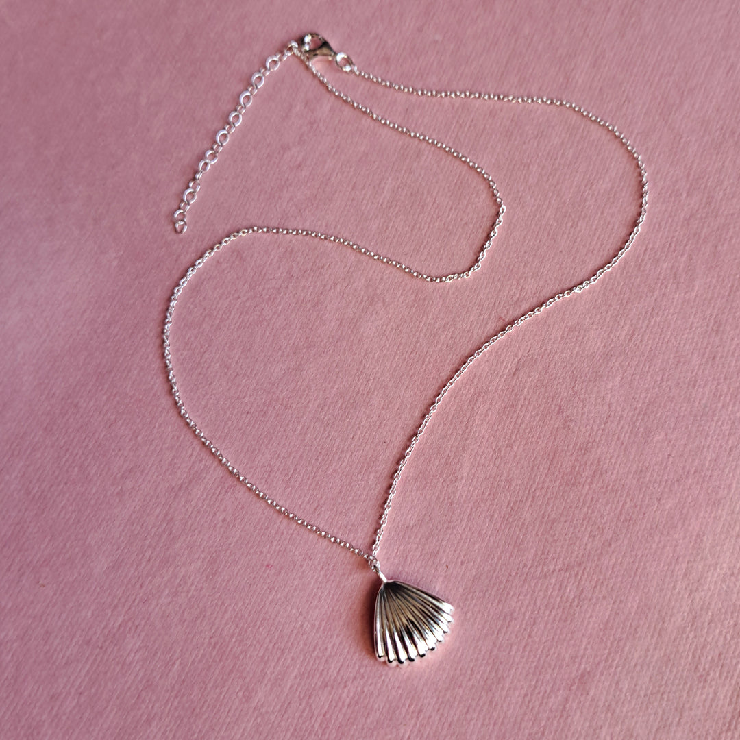 Sterling silver seashell clam pendant necklace on a pink background