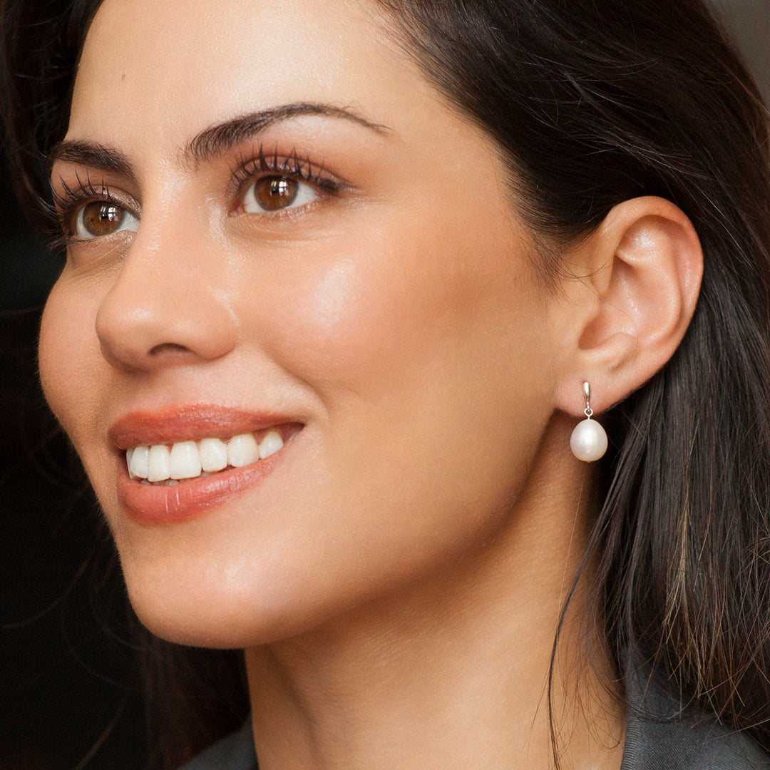 Close-up of a woman wearing silver and pearl earrings 
