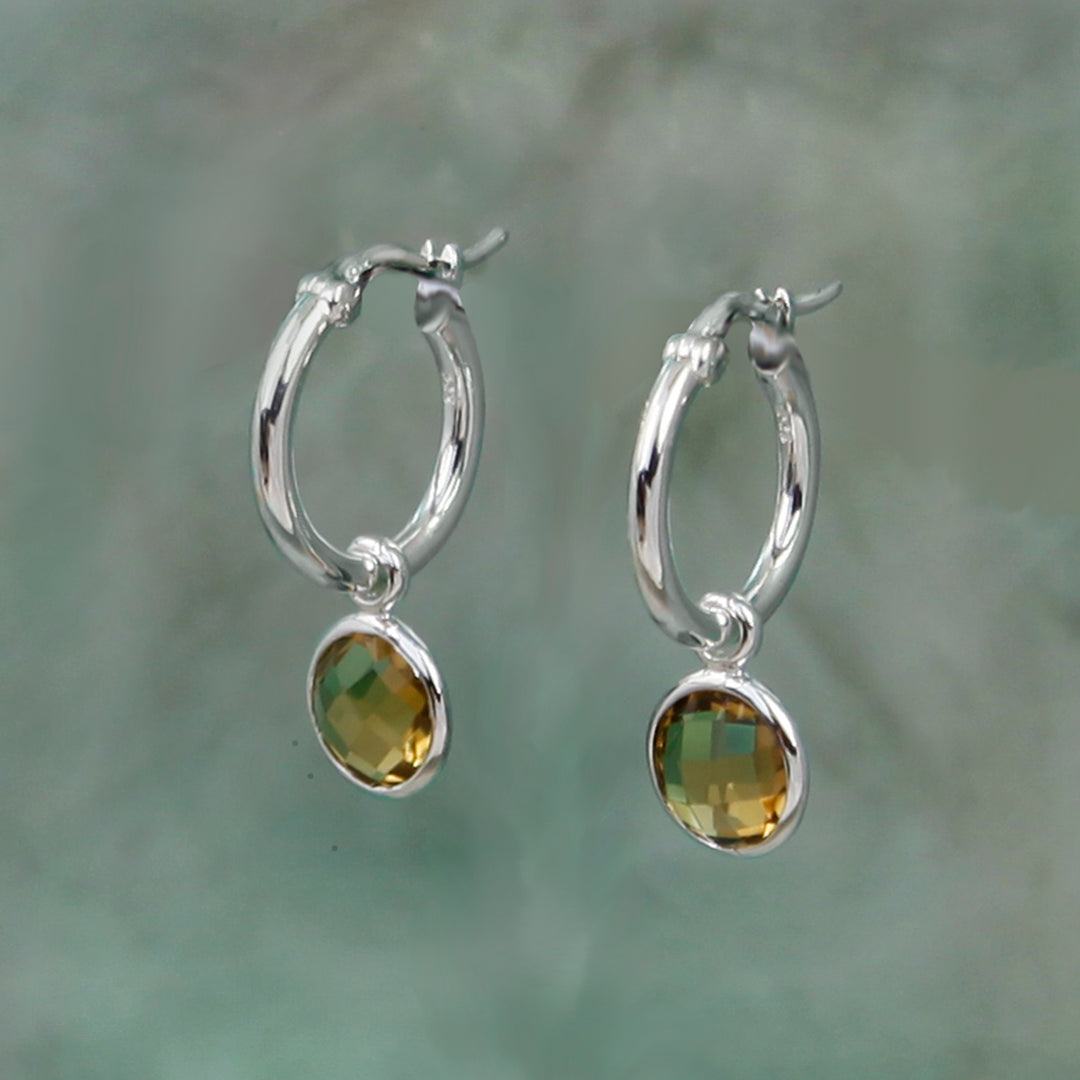 silver snap-post hoop earrings with golden brown gemstone drops on a gray background