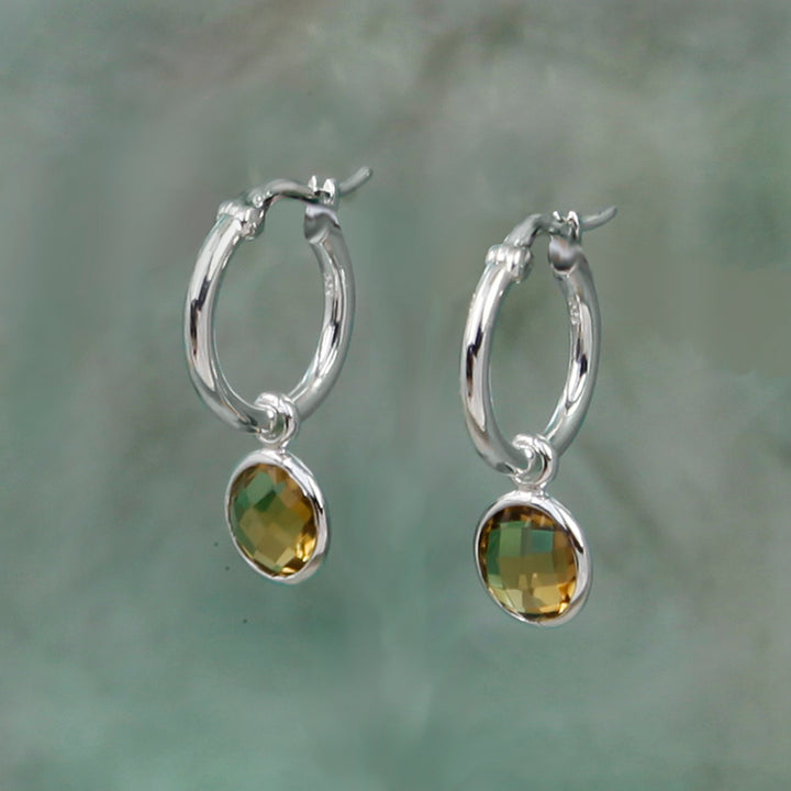 silver snap-post hoop earrings with golden brown gemstone drops on a gray background
