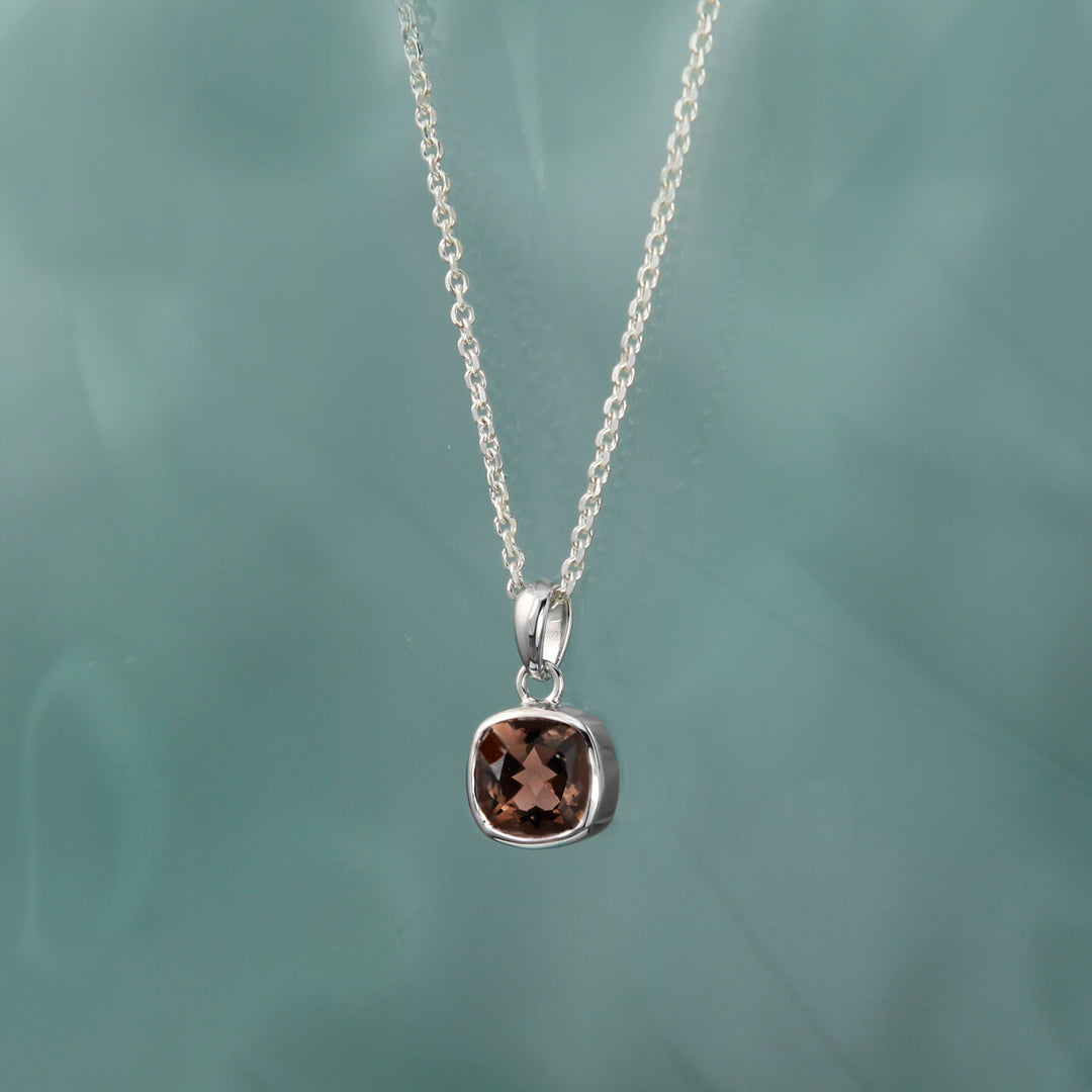 Silver necklace with a pendant featuring a brown gemstone on a green background