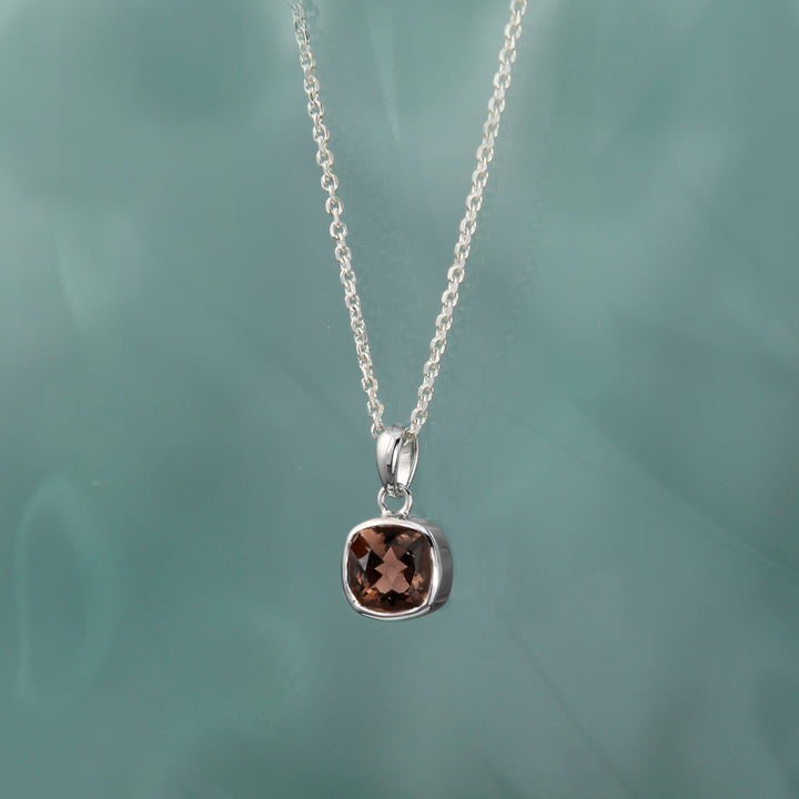 Silver necklace with a pendant featuring a brown gemstone on a green background