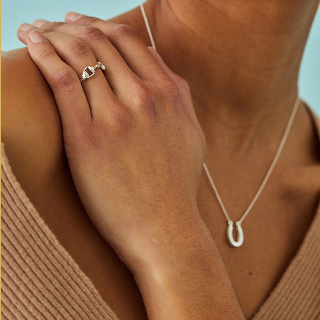 Model wearing equestrian jewellery with silver snaffle bit ring and horseshoe necklace