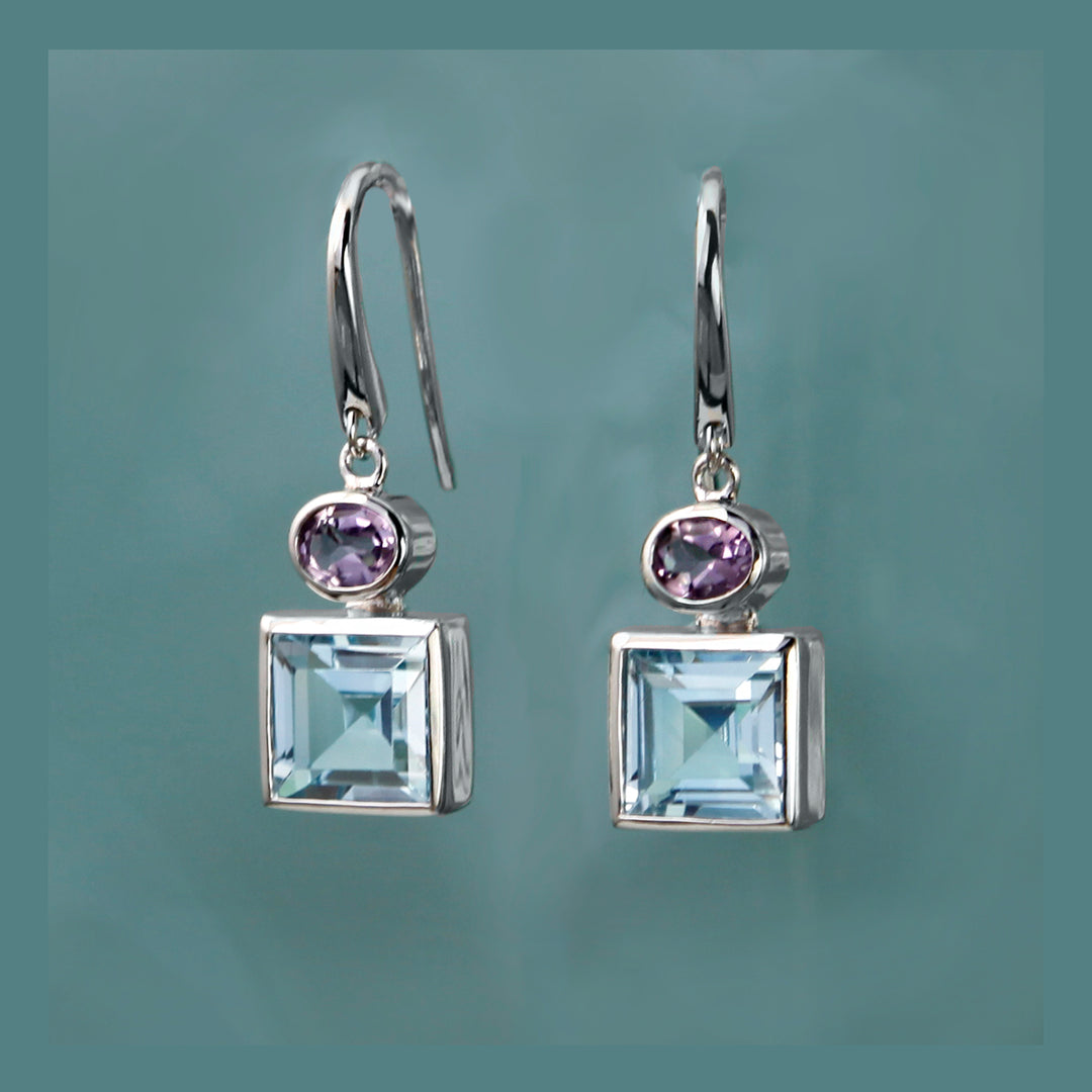 Square silver earrings with blue and purple gemstones on a gray background