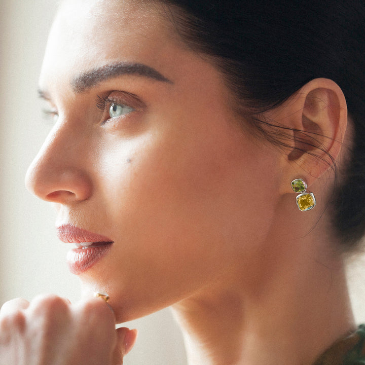 Close of model wearing sterling silver stud earrings with citrine and peridot gemstones