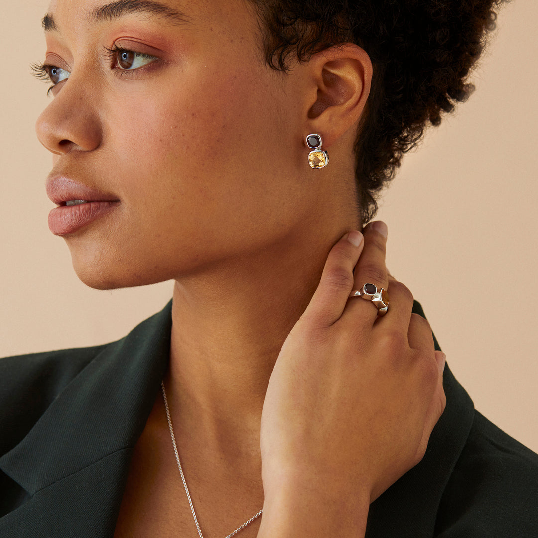 Model wearing silver stud earrings and matching ring with citrine and garnet gemstones