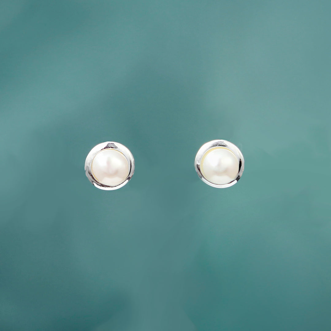 Pair of pearl stud earrings on a teal background