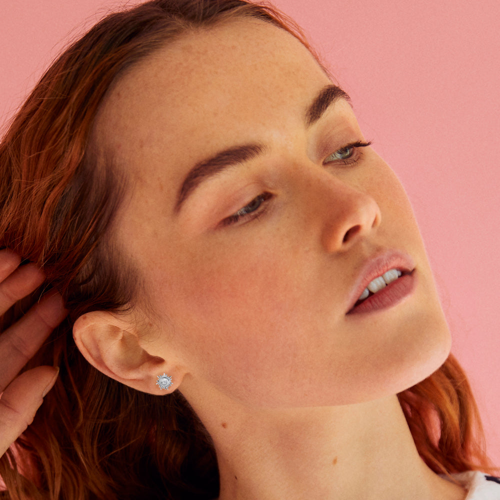 Model wearing silver stun stud earrings with white topaz