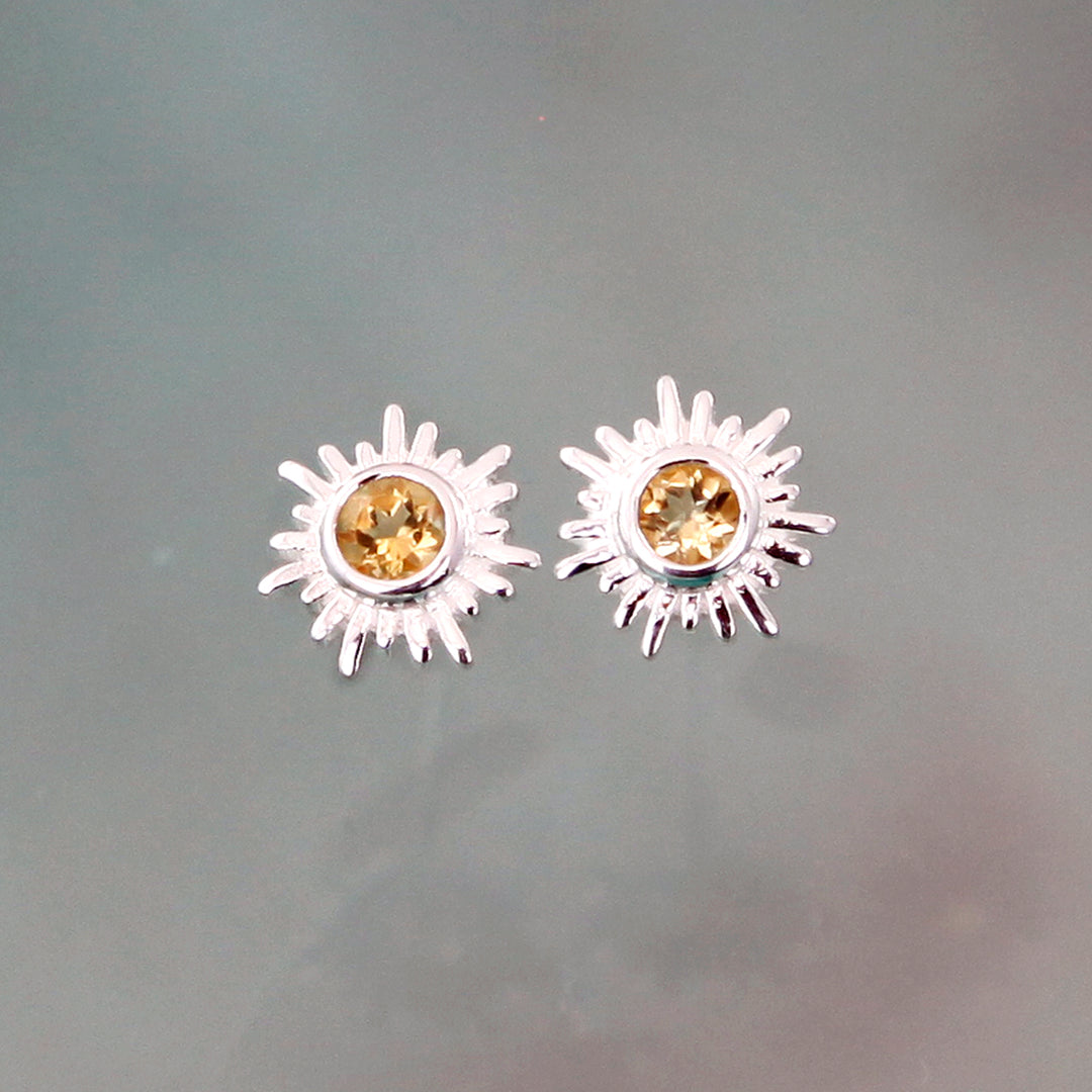 silver sun stud earrings with citrine gems on a gray background