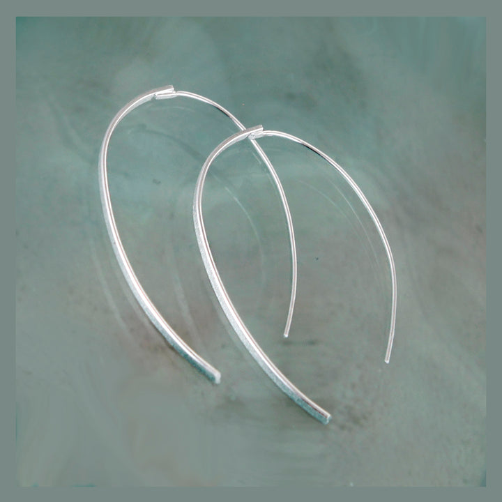 Silver wishbone threader earrings on a textured gray background