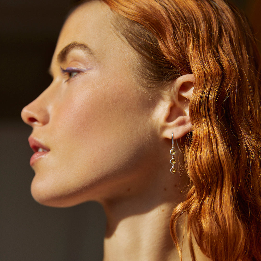 Close-up of model wearing silver dangle earrings with smoky quartz stones
