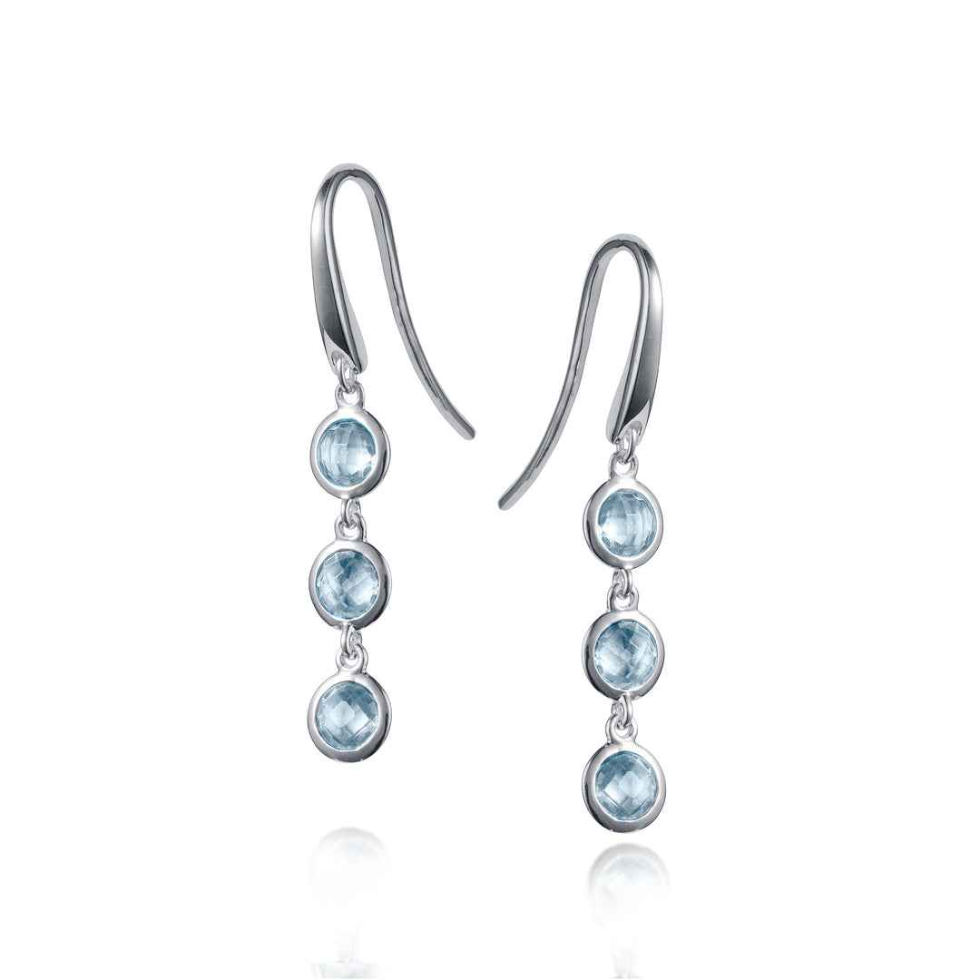 Silver dangle earrings with three blue topaz gemstones on a white background