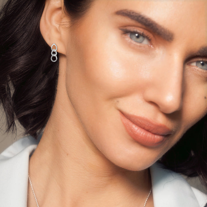 Close-up of model wearing silver pave earrings in a three teardrop design.