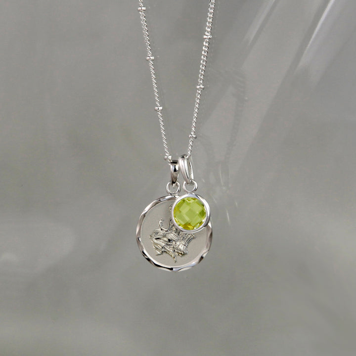 Silver virgo star sign pendant with green peridot August birthstone charm on gray background