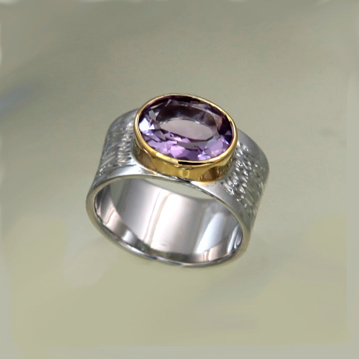 Large sterling silver ring with purple amethyst and gold accent on a light background