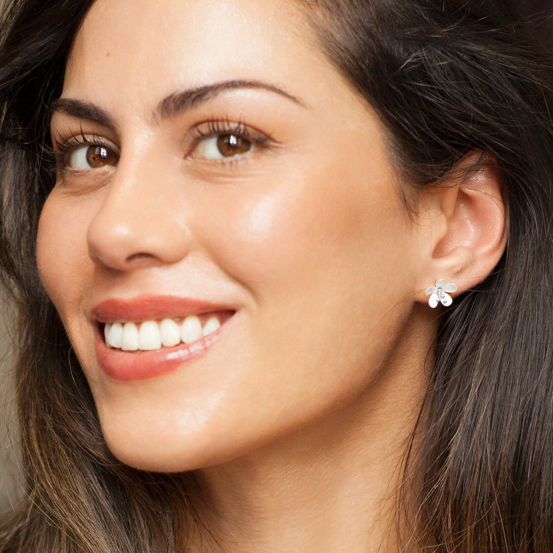 Close-up of a woman wearing a silver flower earring