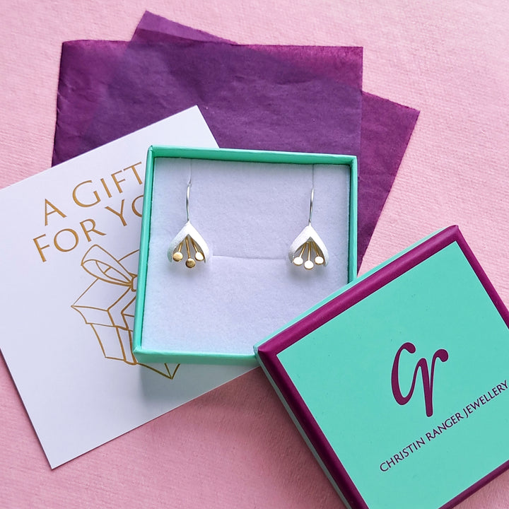 A pair of satin finished snowdrop earrings with gold details in a Christin Ranger Jewellery box with tissue and gift card.